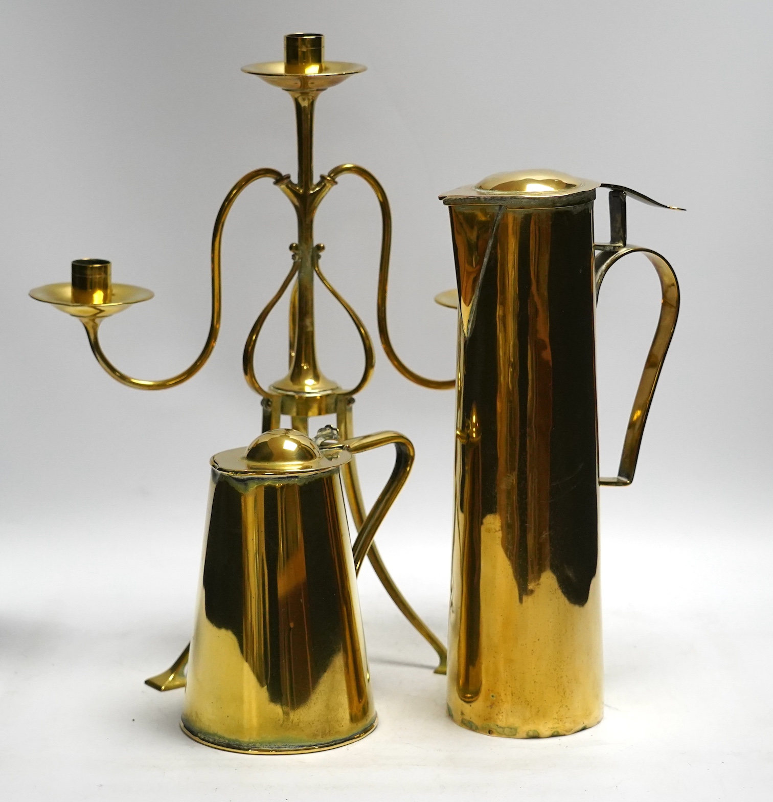 Two brass ewers in Arts and Crafts style and a similar candelabra, 39cm